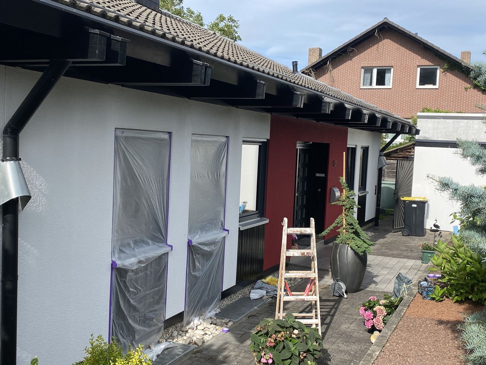Frisch gestrichene Fassade eines Bungalows mit abgeklebten Fenstern