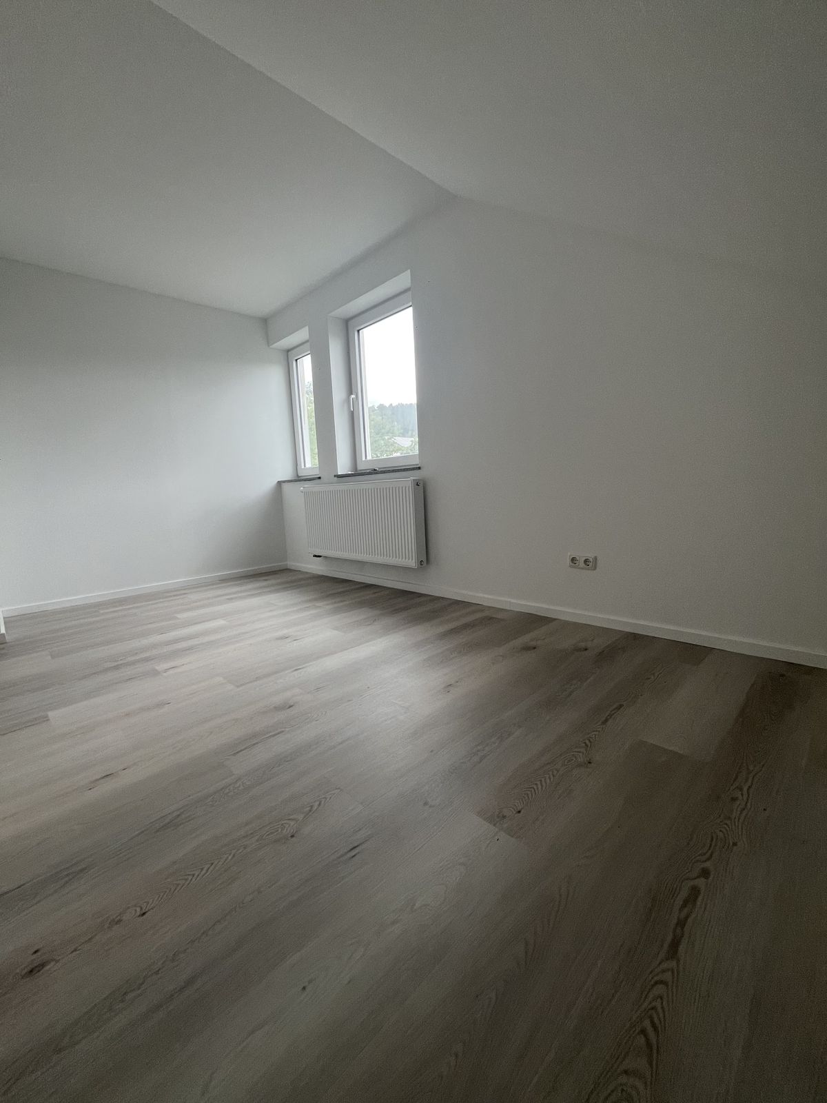 Fertig sanierter Raum im Dachgeschoss mit weißen Wänden und neuem Boden